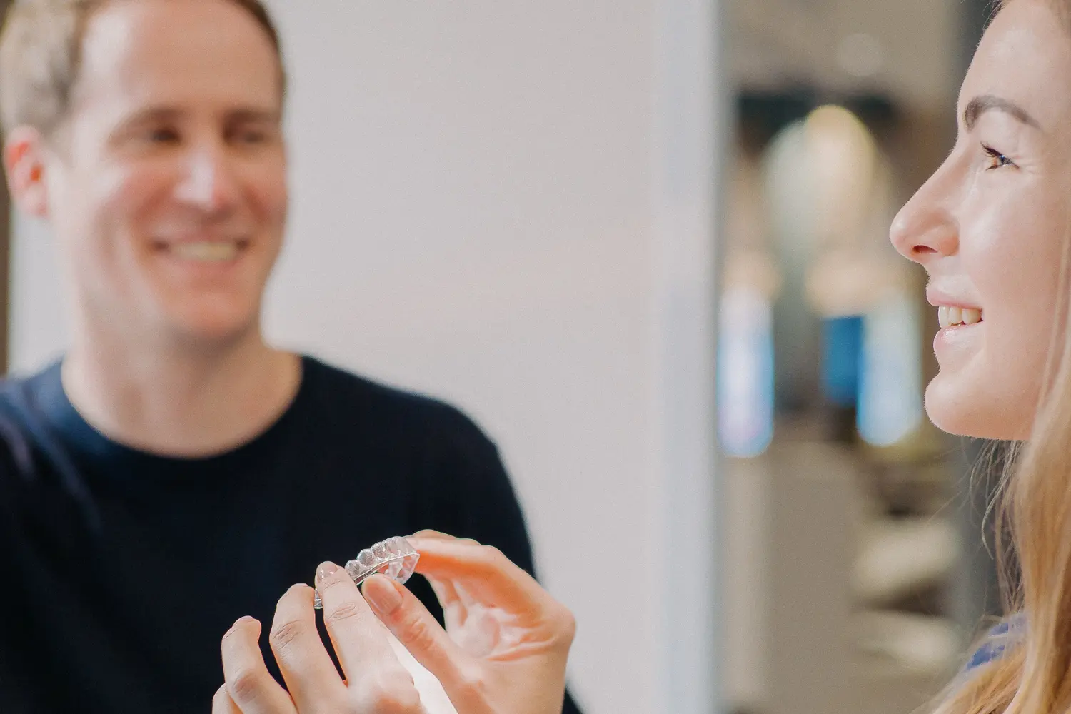 Junge Frau setzt sich in ihrer Behandlung eine transparente Zahnschiene ein 